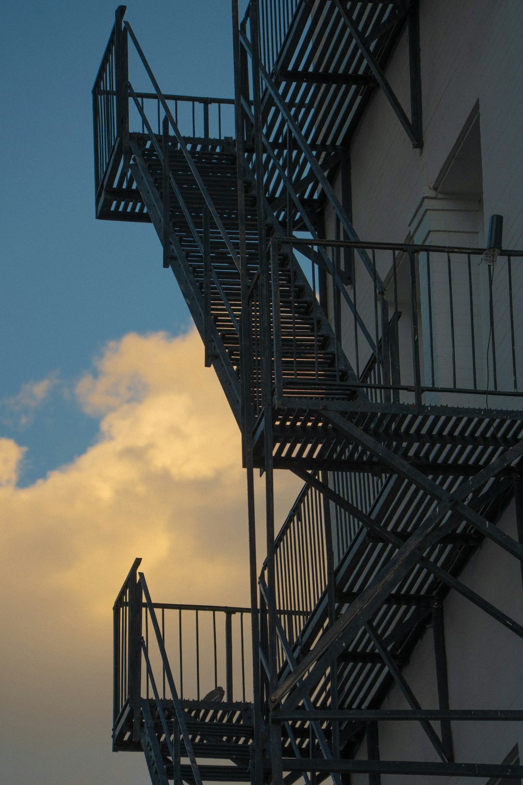 a-metal-fire-escape-against-a-cloudy-sky-jkk6pdi3squ